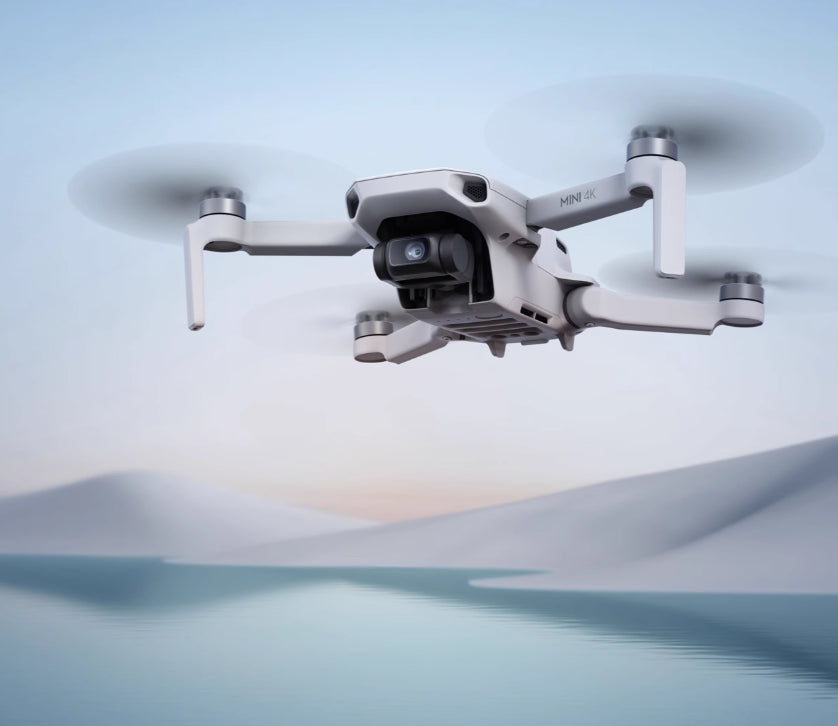 dron Mini 4K DJI flying over a serene lake with mountains in the background