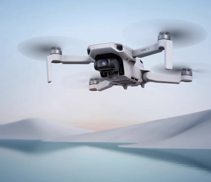dron Mini 4K DJI flying over a serene lake with mountains in the background